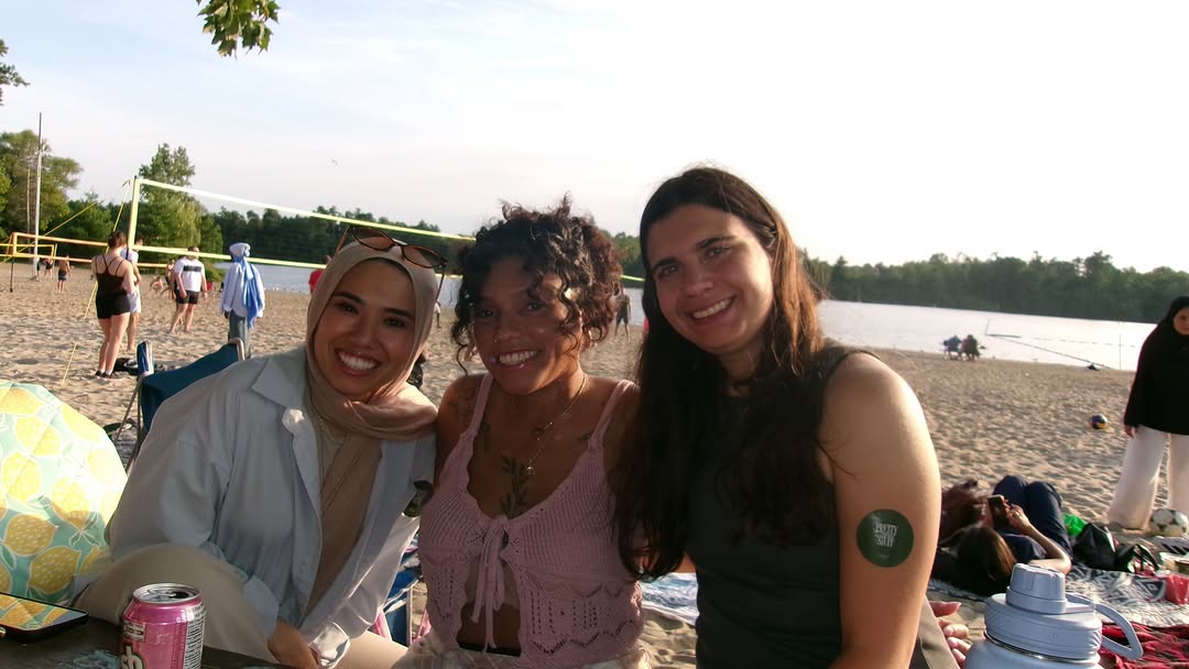 Three friends smiling by the volleyball courts