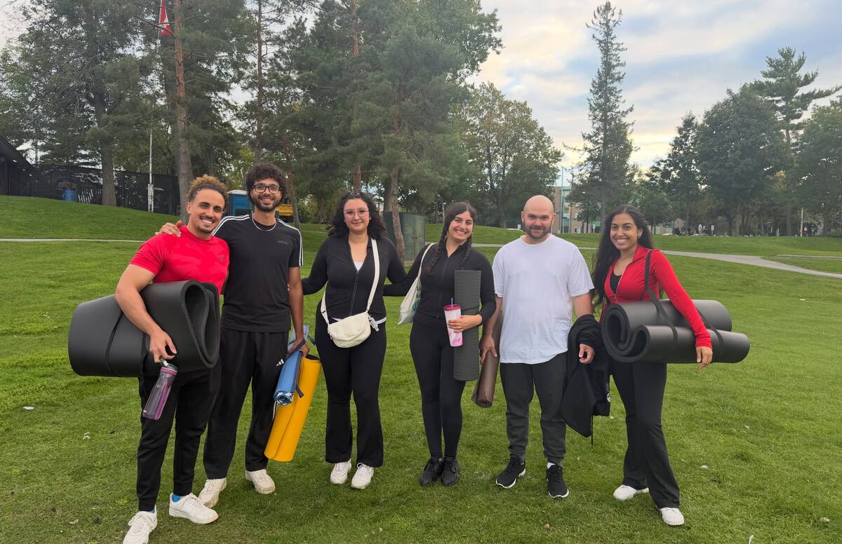 A group of Pilates attendees posing with their rolled-up mats